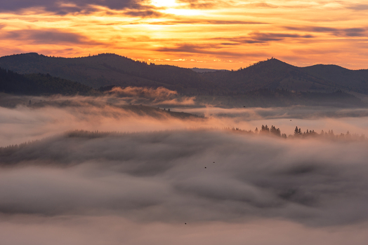 View of the sunset over the misty mountains and dense forests of the Carpathian landscape in Moldovita Suceava County Romania. View of the sunset over the misty mountains and dense forests of the Carpathian landscape in Moldovita Suceava County Romania.