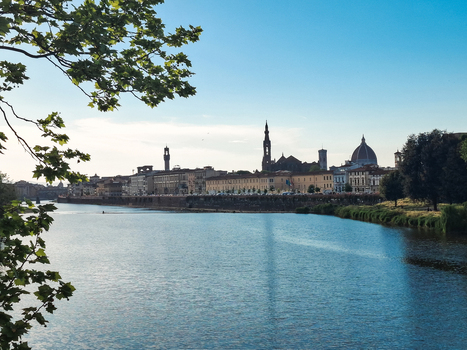 View of the Arno River with the historic skyline of Florence including the Duomo and bell towers under a clear blue sky in Florence Tuscany Italy. View of the Arno River with the historic skyline of Florence including the Duomo and bell towers under a clear blue sky in Florence Tuscany Italy.