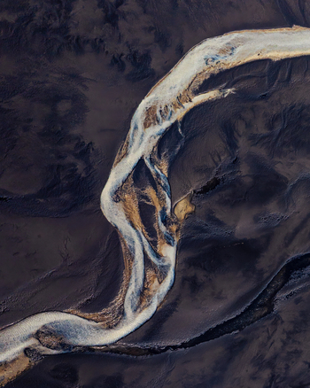 Aerial view of a braided river flowing through dark volcanic sand plains in Iceland. Aerial view of a braided river flowing through dark volcanic sand plains in Iceland.