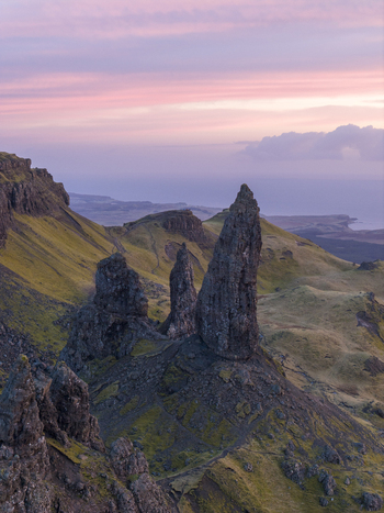 Aerial view of The Storr rock formation with green grassy slopes under a pink sunset sky Isle of Skye Scotland United Kingdom. Aerial view of The Storr rock formation with green grassy slopes under a pink sunset sky Isle of Skye Scotland United Kingdom.