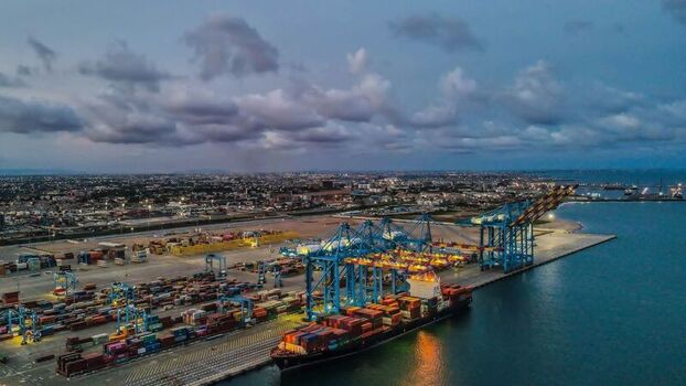 Aerial view of a busy shipping port with large container ships colorful shipping containers and industrial cranes along the coastline in Ghana. Aerial view of a busy shipping port with large container ships colorful shipping containers and industrial cranes along the coastline in Ghana.