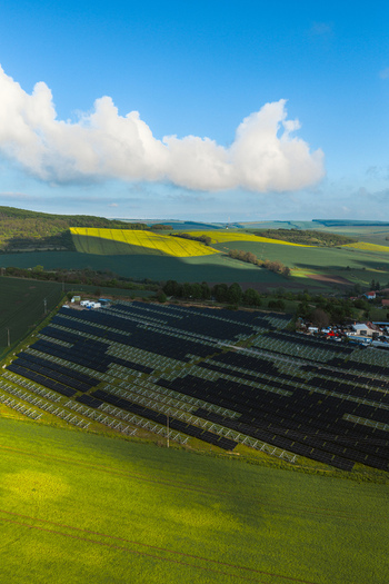 Aerial view of FVE Bohumilice solar power plant surrounded by rolling green hills and yellow rapeseed fields under a blue sky in Klobouky u Brna Jihomoravsky kraj Czechia. Aerial view of FVE Bohumilice solar power plant surrounded by rolling green hills and yellow rapeseed fields under a blue sky in Klobouky u Brna Jihomoravsky kraj Czechia.
