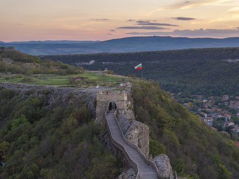 Aerial view of Ovech Fortress with its stone walls and wooden bridge surrounded by lush hills and forest under a soft sunset sky in Provadia Varna Bulgaria. Aerial view of Ovech Fortress with its stone walls and wooden bridge surrounded by lush hills and forest under a soft sunset sky in Provadia Varna Bulgaria.