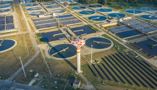 Aerial view of circular settling tanks wastewater treatment basins and solar panel arrays at a large water treatment complex in Italy. Aerial view of circular settling tanks wastewater treatment basins and solar panel arrays at a large water treatment complex in Italy.
