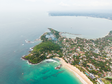Aerial view of the tropical coastline with sandy beaches turquoise ocean waters and lush green palm trees in Mirissa Southern Province Sri Lanka. Aerial view of the tropical coastline with sandy beaches turquoise ocean waters and lush green palm trees in Mirissa Southern Province Sri Lanka.