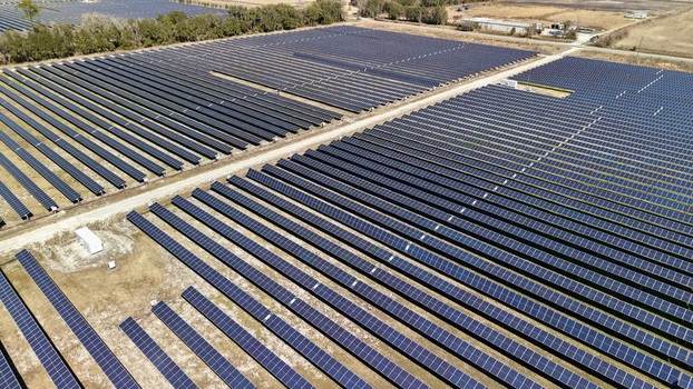 Aerial view of vast solar panel arrays stretch across the landscape reflecting the sky s hue amidst the dry grass Elkton Florida United States. Aerial view of vast solar panel arrays stretch across the landscape reflecting the sky s hue amidst the dry grass Elkton Florida United States.