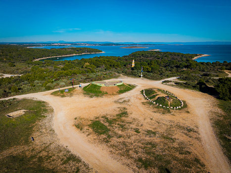 Aerial view of the vibrant green vegetation contrasting against the cerulean sea and the sandy beach painting a picturesque landscape near the coast Kamenjak Istria County Croatia.