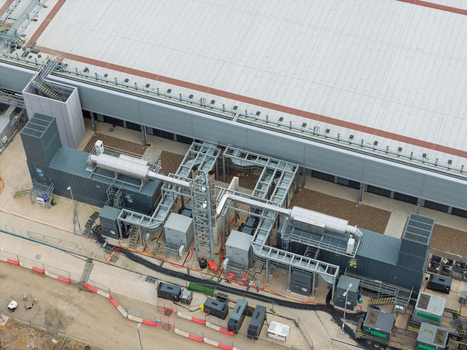 Aerial view of a data center facility featuring industrial cooling systems complex piping and large building rooftops in the United Kingdom.
