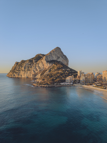 Aerial view of the Penyal d Ifac rock formation rising above the Mediterranean Sea with the coastal town of Calp Valencian Community Spain. Aerial view of the Penyal d Ifac rock formation rising above the Mediterranean Sea with the coastal town of Calp Valencian Community Spain.