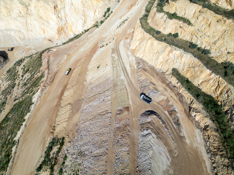 Aerial view of a large open pit quarry with terraced rock walls dirt access roads and heavy machinery operating within the site Teulada Valencian Community Spain.