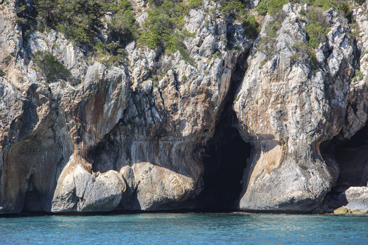 View of Gulf of Orosei with rugged limestone cliffs and a sea cave overlooking turquoise water in Italy. View of Gulf of Orosei with rugged limestone cliffs and a sea cave overlooking turquoise water in Italy.