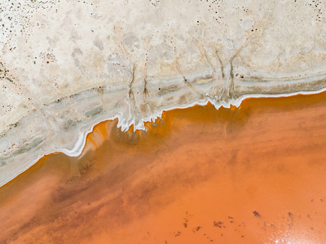 Aerial view of abstract patterns of a salt lake in the Mallee region with vibrant orange water and white mineral deposits along the shoreline Woorinen North Victoria Australia. Aerial view of abstract patterns of a salt lake in the Mallee region with vibrant orange water and white mineral deposits along the shoreline Woorinen North Victoria Australia.