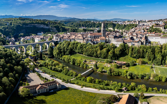 Aerial view of St Nicolas Cathedral and the historic old town with the Sarine river and Zaehringen Bridge surrounded by lush green hills in Fribourg Fribourg Switzerland. Aerial view of St Nicolas Cathedral and the historic old town with the Sarine river and Zaehringen Bridge surrounded by lush green hills in Fribourg Fribourg Switzerland.