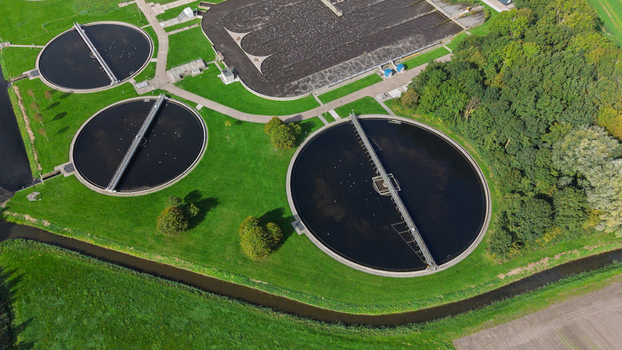 Aerial view of circular wastewater treatment tanks and sedimentation basins surrounded by green grass and trees Warmenhuizen North Holland Netherlands. Aerial view of circular wastewater treatment tanks and sedimentation basins surrounded by green grass and trees Warmenhuizen North Holland Netherlands.