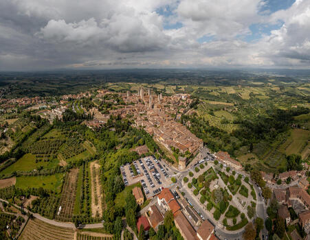 Aerial view of the historic medieval town of San Gimignano with its iconic towers surrounding vineyards and rolling hills of the Tuscan countryside in San Gimignano Tuscany Italy. Aerial view of the historic medieval town of San Gimignano with its iconic towers surrounding vineyards and rolling hills of the Tuscan countryside in San Gimignano Tuscany Italy.