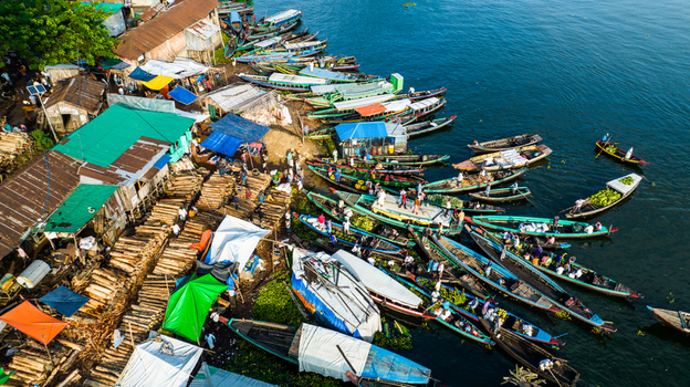 Rangamati Bangladesh 19 October 2022 Aerial view of the bustling riverbank in Rangamati featuring numerous wooden boats loaded with goods and logs with people working along the shore.