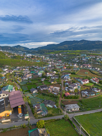 Aerial view of the town of Nuwara Eliya nestled among lush green tea plantations and rolling mountains under a soft sky in Nuwara Eliya Central Province Sri Lanka. Aerial view of the town of Nuwara Eliya nestled among lush green tea plantations and rolling mountains under a soft sky in Nuwara Eliya Central Province Sri Lanka.