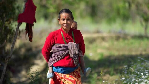 View of a woman carrying a child on her back in Dhangadhi Nepal. View of a woman carrying a child on her back in Dhangadhi Nepal.