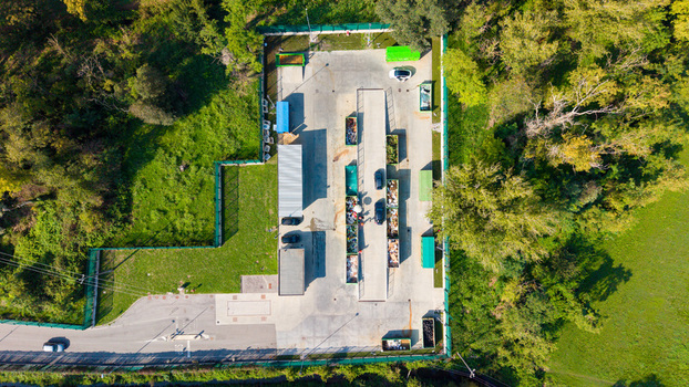 Aerial view of a recyclable waste collection point with various containers and bins arranged in a paved area surrounded by trees in Bettola Zeloforamagno Lombardia Italy. Aerial view of a recyclable waste collection point with various containers and bins arranged in a paved area surrounded by trees in Bettola Zeloforamagno Lombardia Italy.