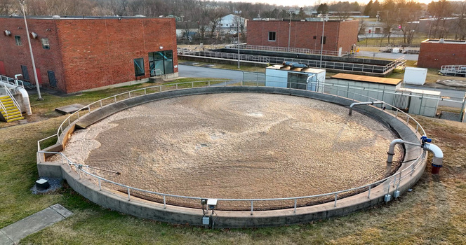 Aerial view of a circular aeration tank at a wastewater treatment plant with brick buildings and industrial infrastructure in Lititz Pennsylvania United States.