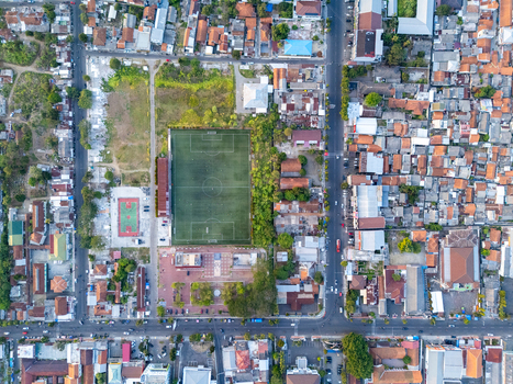 Aerial view of a soccer field surrounded by dense urban housing rooftops and streets in Cilacap Central Java Indonesia. Aerial view of a soccer field surrounded by dense urban housing rooftops and streets in Cilacap Central Java Indonesia.