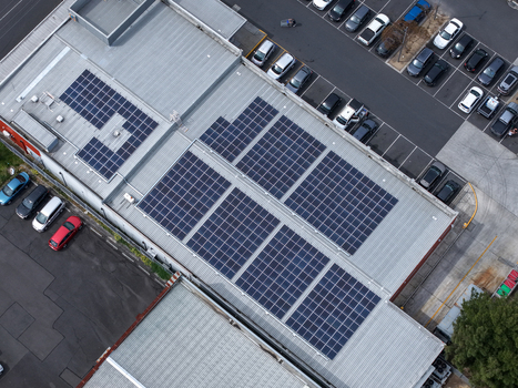 Melbourne VIC Australia 25 September 2026 Aerial view of solar panels installed on a large industrial factory roof with a parking lot filled with cars.