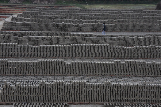 Kushtia District Khulna Division Bangladesh 28 November 2020 View of rows of sun dried bricks arranged in a vast field with a worker walking between them. Kushtia District Khulna Division Bangladesh 28 November 2020 View of rows of sun dried bricks arranged in a vast field with a worker walking between them.