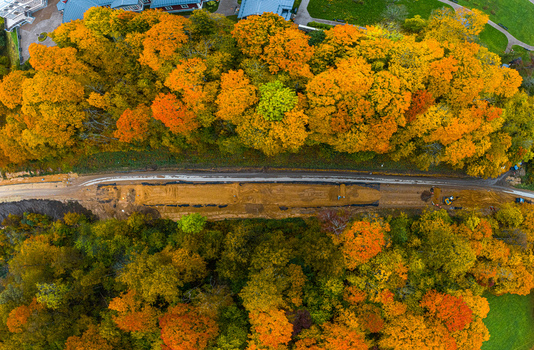 Aerial view of a road construction site surrounded by vibrant autumn forest with colorful foliage in Sigulda Sigulda Municipality Latvia. Aerial view of a road construction site surrounded by vibrant autumn forest with colorful foliage in Sigulda Sigulda Municipality Latvia.