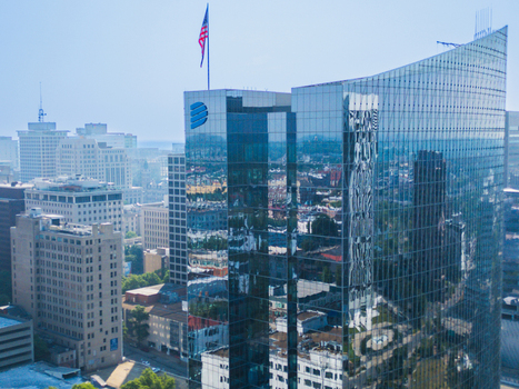 Aerial view of the modern glass skyscraper in Downtown Richmond with the American flag flying on top surrounded by historic city buildings in Richmond Virginia United States. Aerial view of the modern glass skyscraper in Downtown Richmond with the American flag flying on top surrounded by historic city buildings in Richmond Virginia United States.
