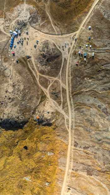 Aerial view of Deosai National Park showing scattered tents dirt tracks and rugged terrain in Skardu Gilgit Pakistan.