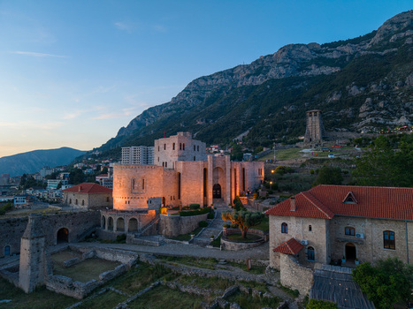 Aerial view of the illuminated Kruje Castle and Skanderbeg Museum with stone walls and red tiled roofs at dusk in Kruje Durres County Albania.