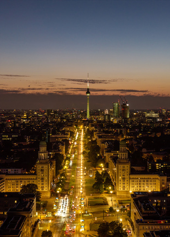 Aerial view of the Berlin skyline at dusk featuring the illuminated Frankfurter Allee leading towards the iconic TV Tower with city lights glowing in Berlin Berlin Germany. Aerial view of the Berlin skyline at dusk featuring the illuminated Frankfurter Allee leading towards the iconic TV Tower with city lights glowing in Berlin Berlin Germany.