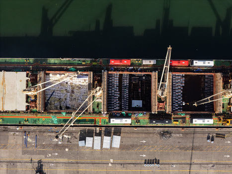 Aerial view of a large cargo ship being loaded with containers and industrial goods by cranes at the busy Haina port in Bajos de Haina San Cristobal Provinc Dominican Republic.