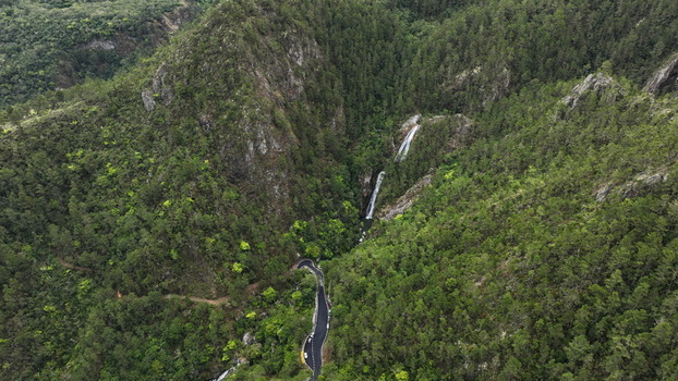 Aerial view of the winding Carretera al Salto de Aguas Blancas road cutting through lush green mountains near the cascading waterfall in Constanza La Vega Dominican Republic. Aerial view of the winding Carretera al Salto de Aguas Blancas road cutting through lush green mountains near the cascading waterfall in Constanza La Vega Dominican Republic.
