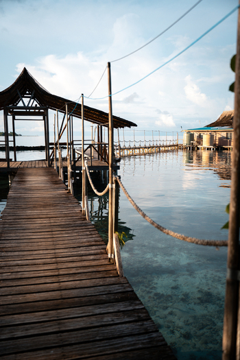 View of a wooden boardwalk stretches out over the crystalline waters inviting exploration towards distant stilt houses Gizo Gizo Solomon Island. View of a wooden boardwalk stretches out over the crystalline waters inviting exploration towards distant stilt houses Gizo Gizo Solomon Island.