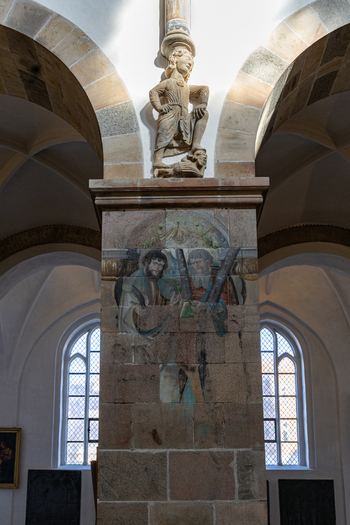 View of the ornate stone pillar featuring religious frescoes and a carved sculpture inside the historic Ribe Cathedral Ribe Denmark. View of the ornate stone pillar featuring religious frescoes and a carved sculpture inside the historic Ribe Cathedral Ribe Denmark.