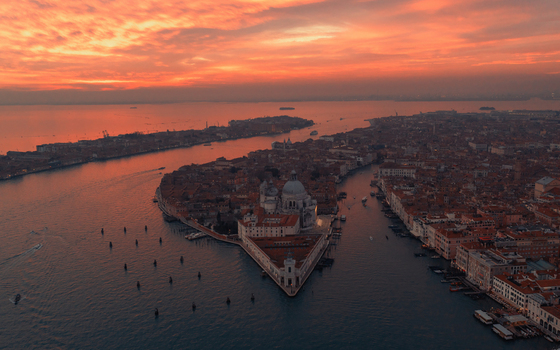 Aerial view of Santa Maria della Salute and the historic city of Venice at sunset with vibrant orange sky reflecting on the water Venice Veneto Italy. Aerial view of Santa Maria della Salute and the historic city of Venice at sunset with vibrant orange sky reflecting on the water Venice Veneto Italy.
