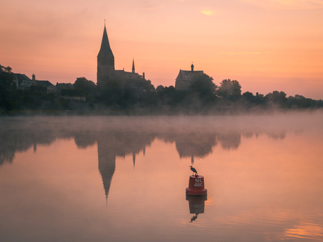View of the silhouette of Kessel village with its church spire and castle reflected in the misty Meuse river at sunrise Kessel Limburg Netherlands. View of the silhouette of Kessel village with its church spire and castle reflected in the misty Meuse river at sunrise Kessel Limburg Netherlands.