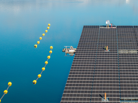 Aerial view of the floating solar farm at Cottbuser Ostsee with workers performing repairs on the panels surrounded by yellow safety buoys on the water in Cottbus Brandenburg Germany. Aerial view of the floating solar farm at Cottbuser Ostsee with workers performing repairs on the panels surrounded by yellow safety buoys on the water in Cottbus Brandenburg Germany.