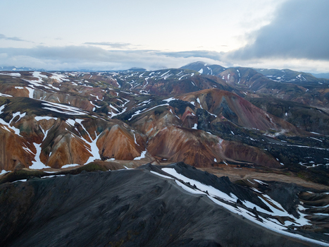 Aerial view of Landmannalaugar featuring colorful rhyolite mountains with patches of snow under a cloudy sky in Rangarthing ytra Iceland. Aerial view of Landmannalaugar featuring colorful rhyolite mountains with patches of snow under a cloudy sky in Rangarthing ytra Iceland.