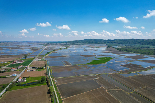 Aerial view of the flooded rice fields surrounding the Abbazia di Lucedio with distant hills and a blue sky in Trino Piemonte Italy.