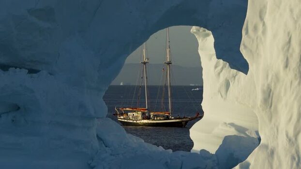 Aerial view of sailboat framed by arch iceberg Greenland. Aerial view of sailboat framed by arch iceberg Greenland.