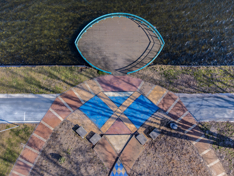 Aerial view of a decorative walkway with geometric patterns leading to an oval shaped structure on the water reflecting the sunlight Maastrichtkwartier Flevoland Netherlands. Aerial view of a decorative walkway with geometric patterns leading to an oval shaped structure on the water reflecting the sunlight Maastrichtkwartier Flevoland Netherlands.
