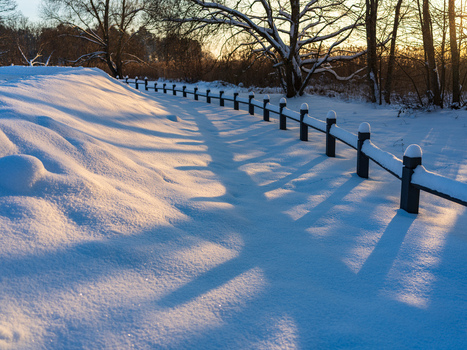 View of a snow covered path lined with a wooden fence under the golden hour light in Trakai Vilnius County Lithuania. View of a snow covered path lined with a wooden fence under the golden hour light in Trakai Vilnius County Lithuania.