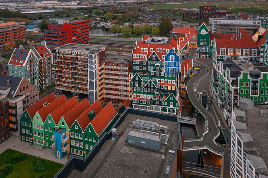 Zaandam Netherlands 26 April 2022 Aerial view of Inntel Hotels Amsterdam Zaandam with its unique stacked green house facade surrounding urban architecture and winding waterways at dusk.