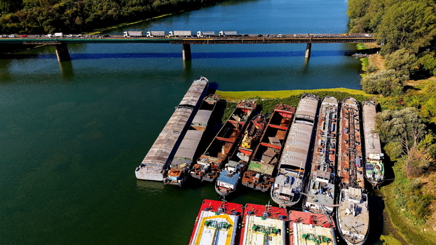 Aerial view of Smederevo Fortress area on the Danube river featuring several cargo barges moored along the riverbank near a bridge with traffic in Smederevo Podunavlje District Serbia.