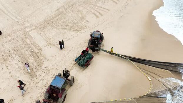 Aerial view of tractors pulling fishing nets on the beach Portugal. Aerial view of tractors pulling fishing nets on the beach Portugal.