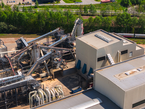 Aerial view of an industrial facility with complex conveyor systems large factory buildings and silos surrounded by green trees in Jihlava Vysocina Region Czechia.