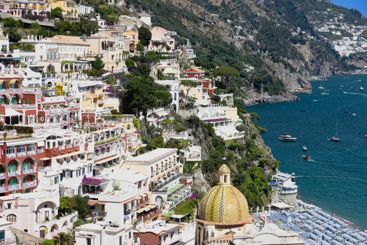 Aerial view of the colorful hillside architecture of Positano featuring the iconic tiled dome of the Church of Santa Maria Assunta overlooking the Tyrrhenian Sea in Positano Campania Italy. Aerial view of the colorful hillside architecture of Positano featuring the iconic tiled dome of the Church of Santa Maria Assunta overlooking the Tyrrhenian Sea in Positano Campania Italy.