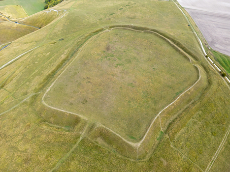 Aerial view of the Iron Age hillfort of Uffington Castle with its prominent earthwork ramparts and the nearby Uffington White Horse in the rolling hills of Faringdon England United Kingdom. Aerial view of the Iron Age hillfort of Uffington Castle with its prominent earthwork ramparts and the nearby Uffington White Horse in the rolling hills of Faringdon England United Kingdom.